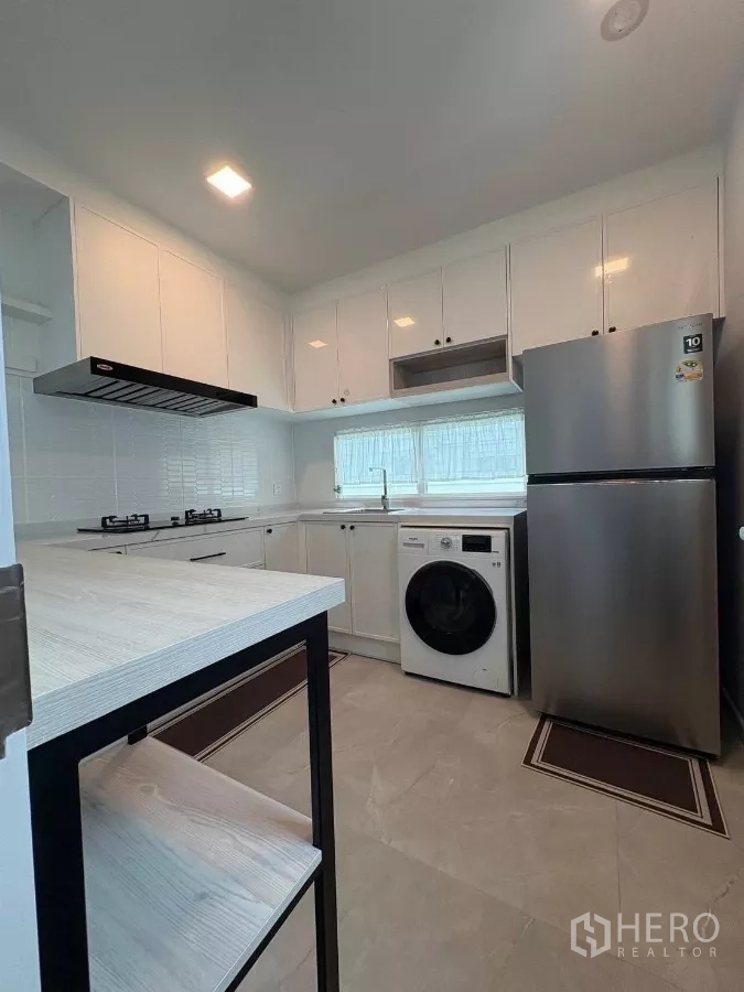 Detached House for rent or sale in Bang Phli, Samut Prakan - Fully fitted kitchen with white cabinets, gas hob, fridge and washer.