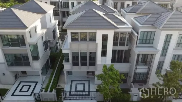 Detached House for rent in Prawet, Bangkok - Aerial view of modern three‑storey semi‑detached houses with geometric paved driveways and landscaped frontage.