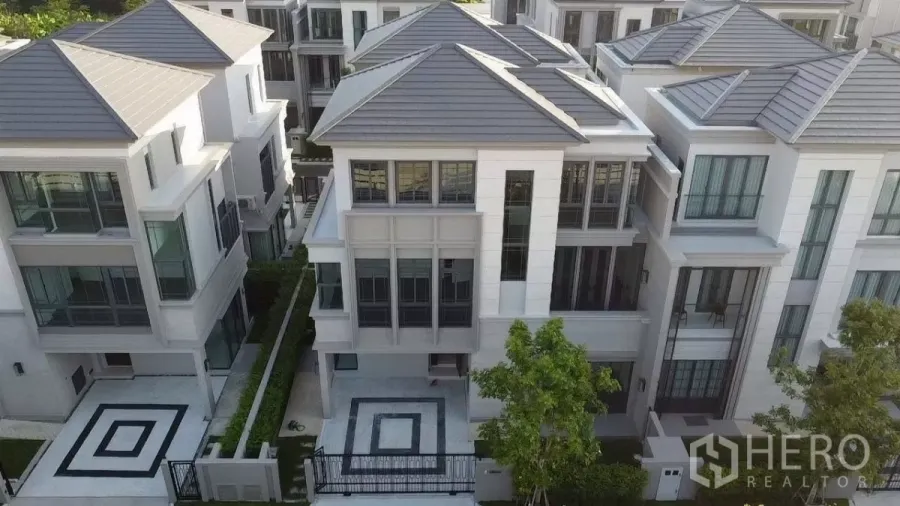 Detached House for rent in Prawet, Bangkok - Aerial view of modern three‑storey semi‑detached houses with geometric paved driveways and landscaped frontage.