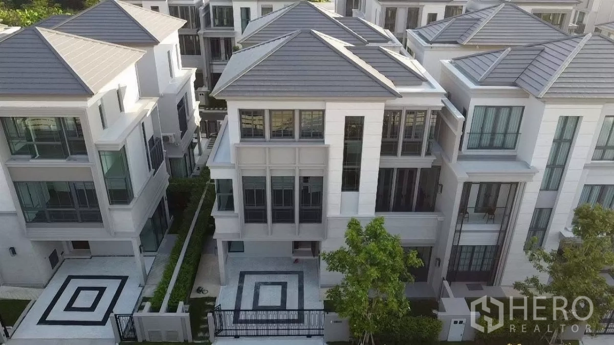Detached House for rent in Prawet, Bangkok - Aerial view of modern three‑storey semi‑detached houses with geometric paved driveways and landscaped frontage.
