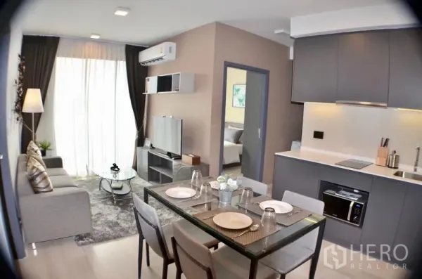 คอนโด ให้เช่าในWatthana, Bangkok - พื้นที่นั่งเล่น-รับประทานอาหารแบบเปิดโล่ง พร้อมครัวบิลท์อินสีเทาและโต๊ะกระจก 4 ที่นั่ง