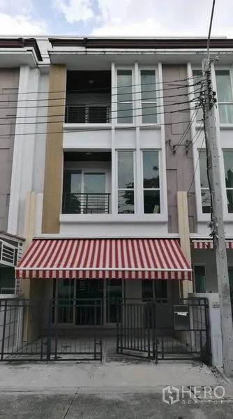 Townhouse for rent in Wang Thonglang, Bangkok - Three-storey modern townhouse facade with red-and-white awning and gated parking in Wang Thonglang.
