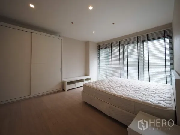 公寓 出租在Watthana, Bangkok - 明亮卧室，落地窗与百叶，配滑门衣柜。