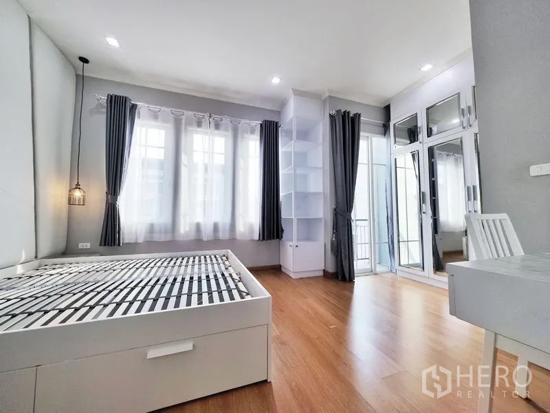 联排别墅 出租或出售在Phra Pradaeng, Samut Prakan - 主卧一角，可见阳台门、镜面衣柜与书架。