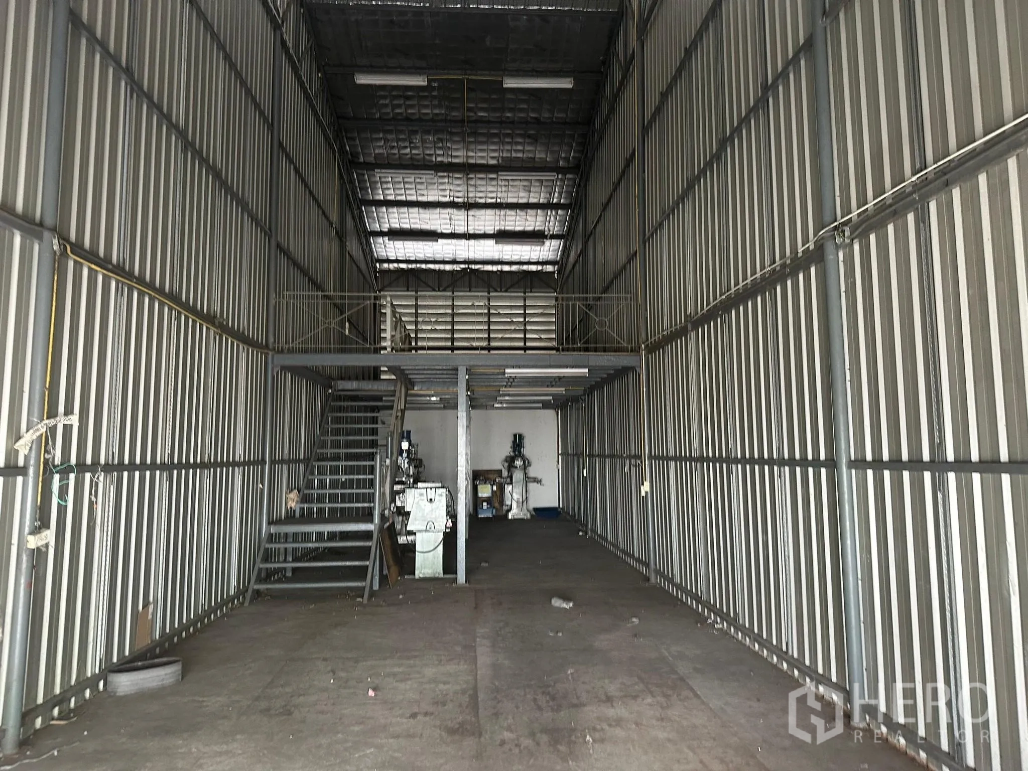 Warehouse for rent in Huai Khwang, Bangkok - Tall steel-clad warehouse bay with mezzanine platform and stairs.