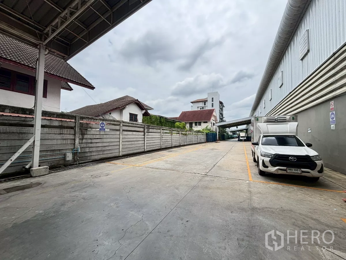Warehouse for rent in Bang Sue, Bangkok - Exterior loading driveway beside the warehouse with marked parking bays and box trucks.