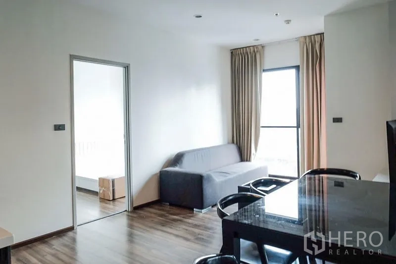 公寓 出租在Khlong Toei, Bangkok - 开放式起居与用餐区，沙发与高窗相连通向阳台。