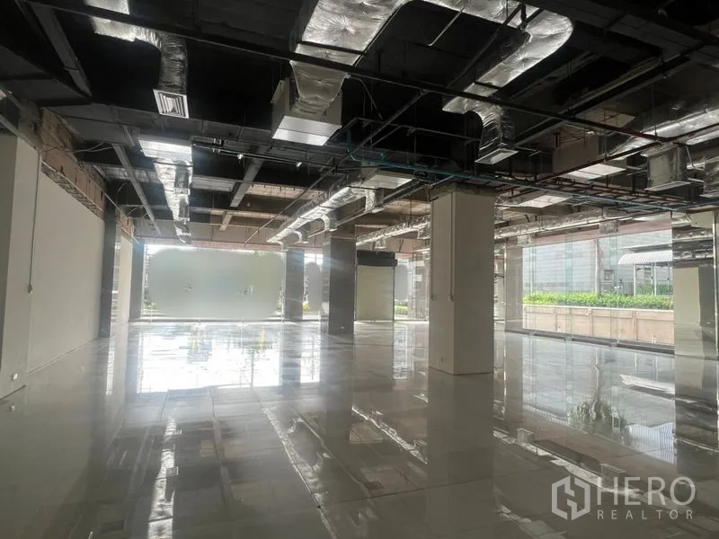 零售空间 出租 - 采光充足的零售大厅，反光地面、结构柱与大面积窗户。