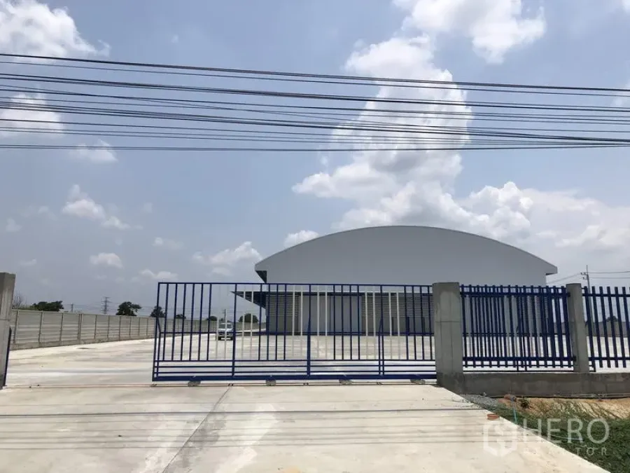 Factory for rent or sale in Lat Lum Kaeo, Pathum Thani - Blue steel entrance gate opening to a spacious forecourt and perimeter wall.