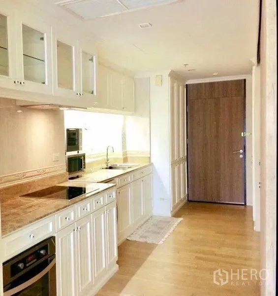 คอนโด ให้เช่าในKhlong Toei, Bangkok - โถงครัวพร้อมเตาอบ เตาไฟฟ้า เคาน์เตอร์หิน ตู้กระจก และพื้นไม้สีน้ำตาล อมใกล้ประตูเข้าห้อง