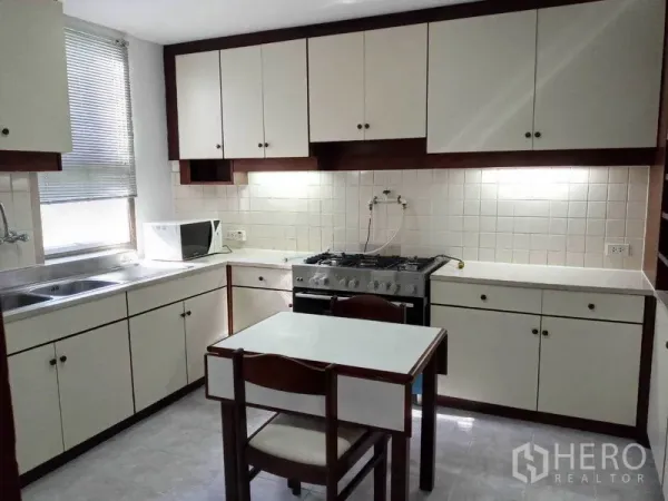 คอนโด ให้เช่าในWatthana, Bangkok - ครัวรูปตัวแอล ตู้บิลท์อินสีขาว เตาแก๊ส หน้าต่าง และโต๊ะทานข้าวเล็ก