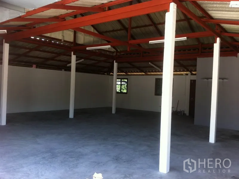 货栈 出租在Lam Luk Ka, Pathum Thani - 仓库内部空间开阔，红色钢结构屋架、白色立柱与混凝土地面。