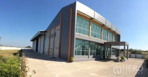 โรงงาน ขายในBang Sao Thong, Samut Prakan - ภาพกว้างของอาคารโรงงานพร้อมลานคอนกรีตกว้างและพื้นที่สวน.