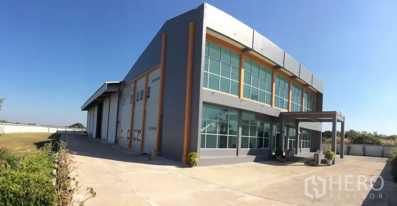 โรงงาน ขายในBang Sao Thong, Samut Prakan - ภาพกว้างของอาคารโรงงานพร้อมลานคอนกรีตกว้างและพื้นที่สวน.