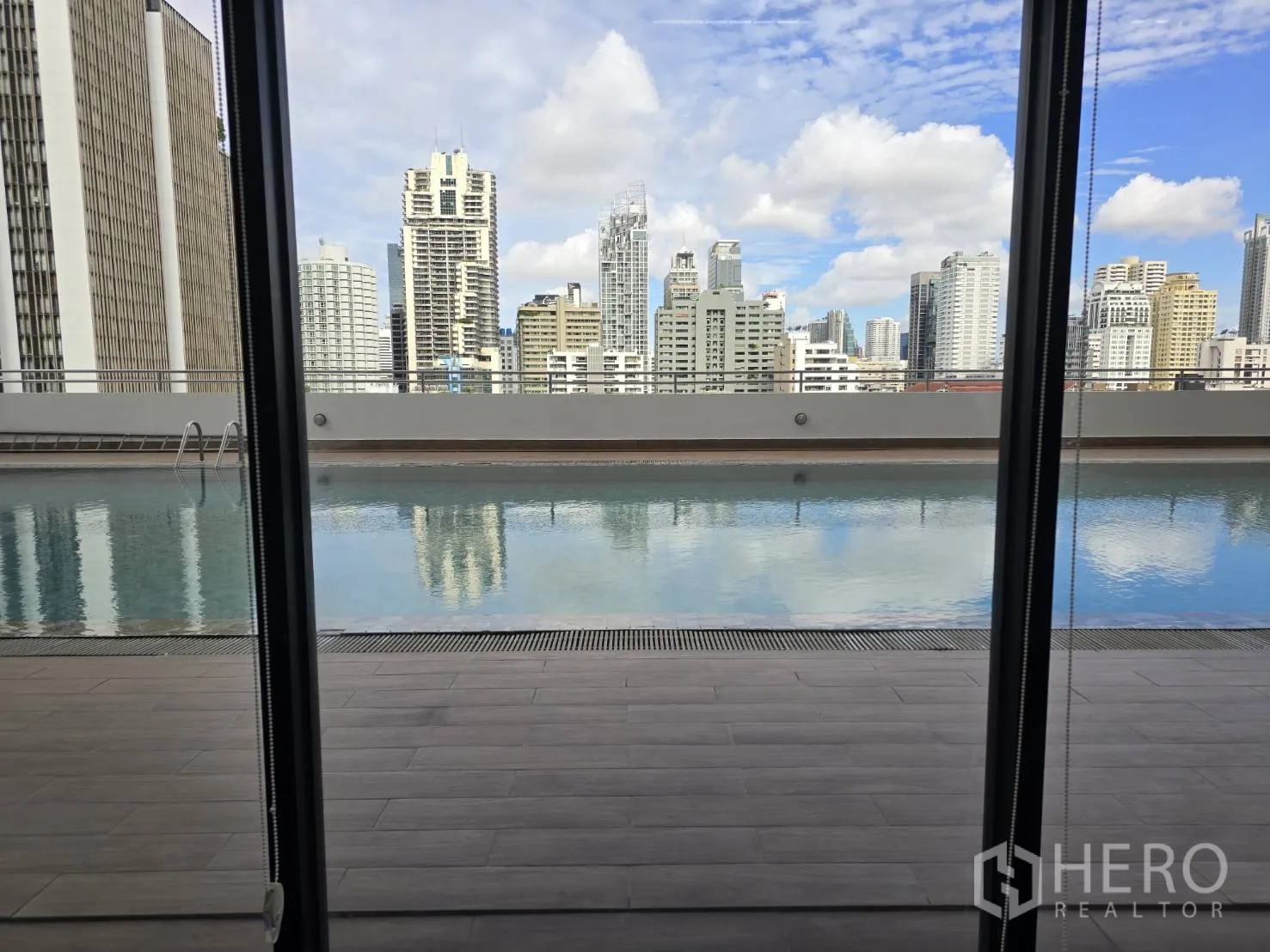 Office Space for rent in Watthana, Bangkok - Rooftop swimming pool and city skyline seen through floor-to-ceiling windows.