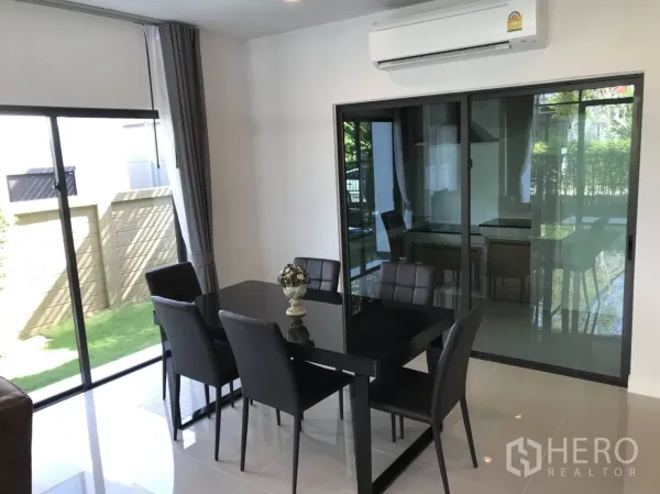 Detached House for rent in Bang Kapi, Bangkok - Dining space with black table and four chairs beside sliding doors and an air-conditioning unit.