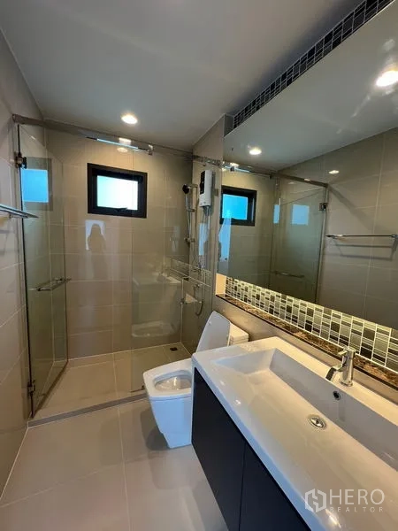 Detached House for rent in Bang Kapi, Bangkok - Bathroom with walk-in glass shower, long mirror and vanity cabinet.