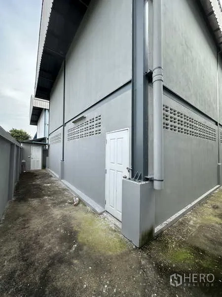 คลังสินค้า ให้เช่าในPak Kret, Nonthaburi - ทางเดินด้านข้างอาคาร พร้อมประตูบริการและผนังคอนกรีต