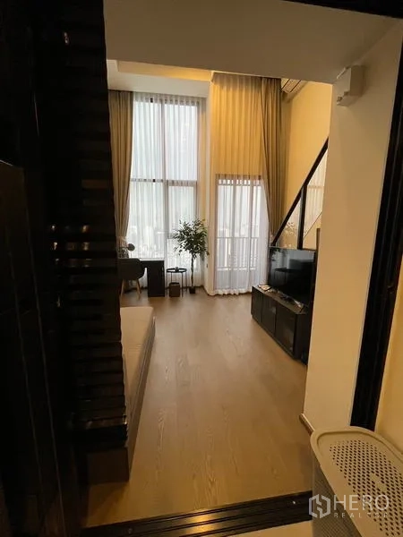 公寓 出租在Bang Rak, Bangkok - 从入口望向明亮客厅，超高窗帘与玻璃阳台门。