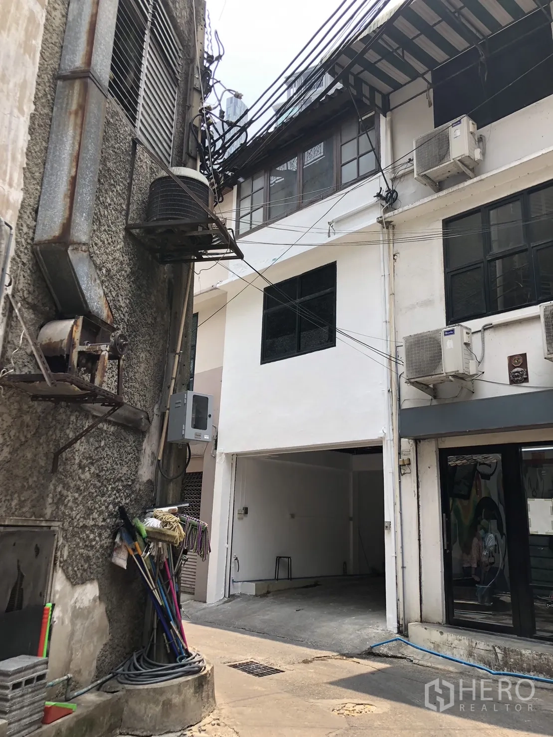 อาคารพาณิชย์ ให้เช่า - ด้านนอกริมซอยของอาคารพาณิชย์สีขาว มีหน้าต่างชั้นบนและคอมเพรสเซอร์แอร์
