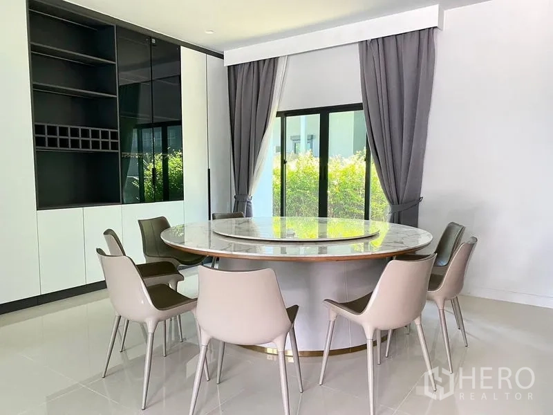 Detached House for sale in Bang Kapi, Bangkok - Dining room close-up showing a marble-topped round table and built-in storage wall.