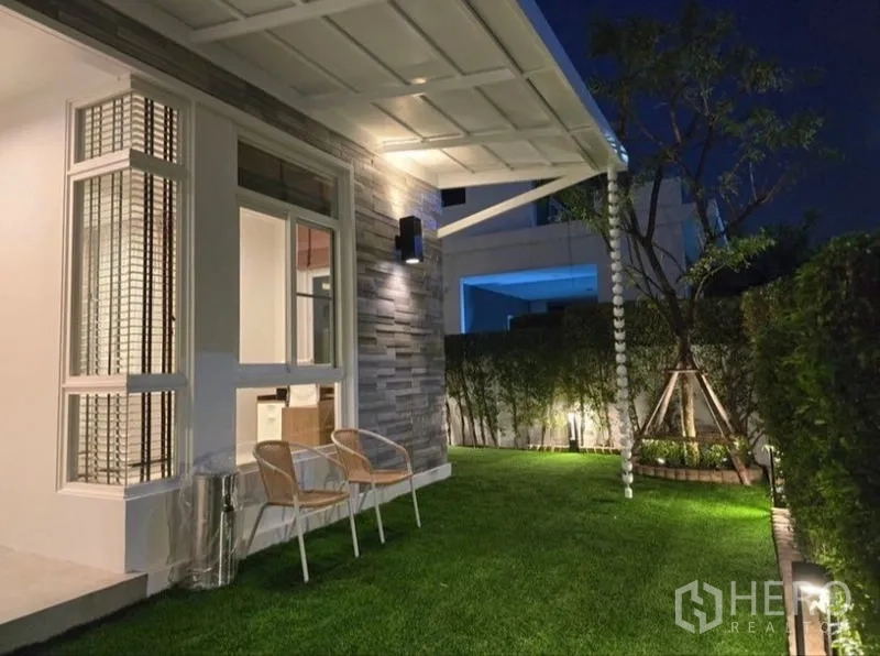 独立式住宅 出租 - 夜景花园，带雨棚与壁灯，草坪上设有休闲座椅。