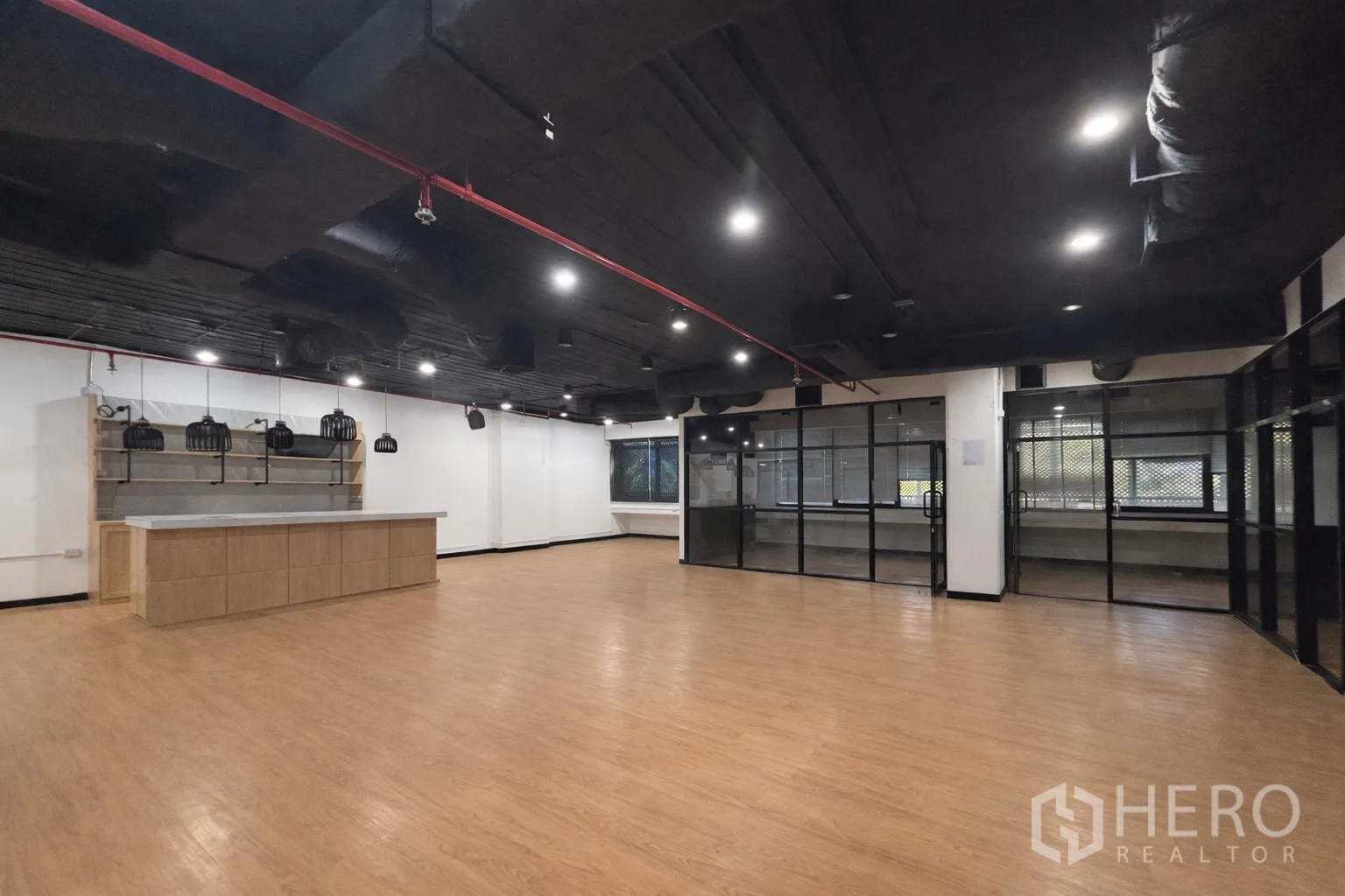 Office Space for rent in Bang Rak, Bangkok - Open-plan office with wood-look flooring, black exposed ceiling, pantry counter, and glass partitions.