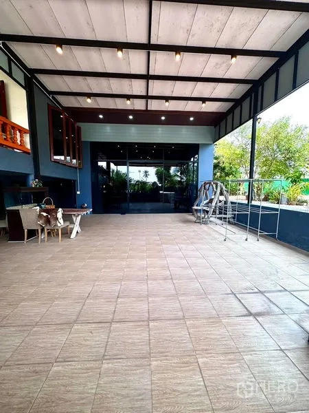 Detached House for sale in Bang Bua Thong, Nonthaburi - Covered tiled terrace with high roof and sliding glass doors to the interior.
