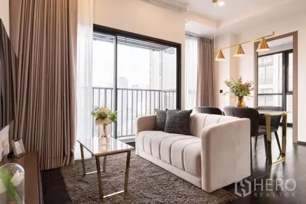 公寓 出租在Watthana, Bangkok - 采光充足的客厅，米色沙发、玻璃茶几与带城市景观的阳台