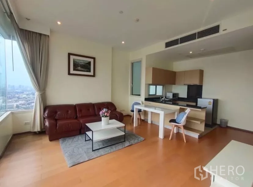 Condominium for rent in Chatuchak, Bangkok - Cozy living area with leather sofa, dining table and built-in kitchen cabinetry.