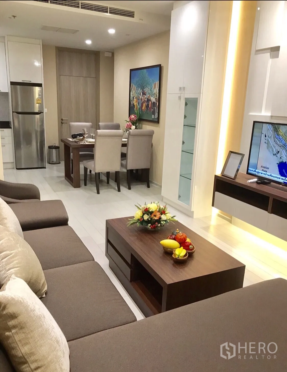 Condominium for rent in Pathum Wan, Bangkok - Open-plan living and dining area with sectional sofa, TV wall and a four-seat dining set.