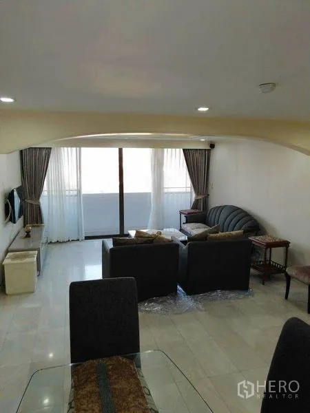 Condominium for rent in Watthana, Bangkok - Bright living room opening to a balcony through sliding glass doors.
