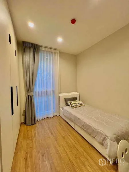 Condominium for sale in Watthana, Bangkok - Guest bedroom with wardrobe, single bed and floor-to-ceiling window.