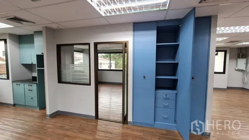 Office Space for rent in Watthana, Bangkok - Built-in blue storage cabinets beside a glass-partitioned room.