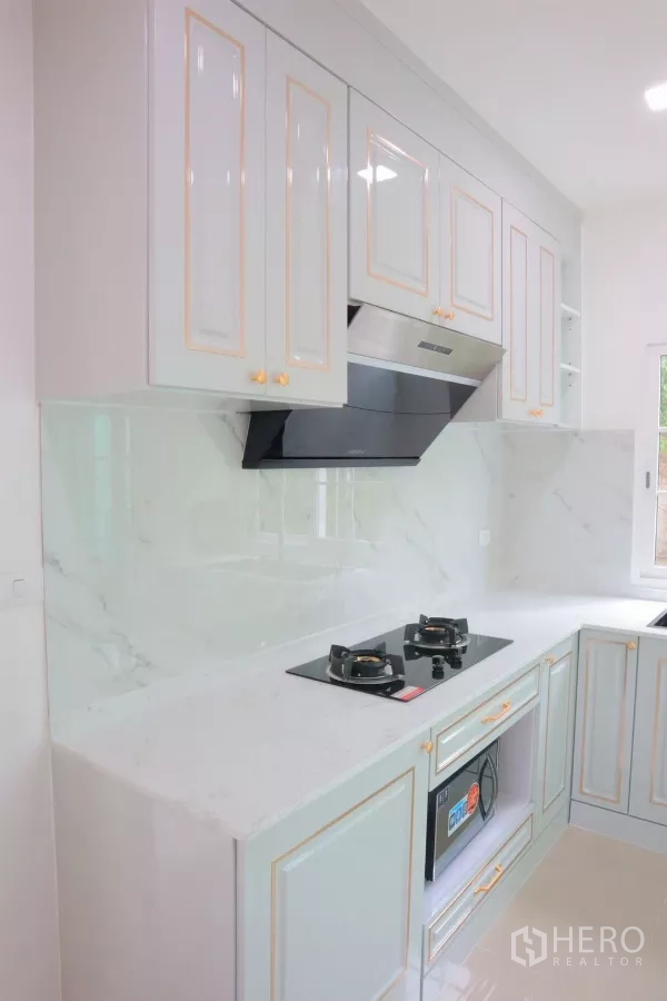 Detached House for rent in Bang Phli, Samut Prakan - Close-up of built-in kitchen cabinets, cooktop, hood and marble backsplash.