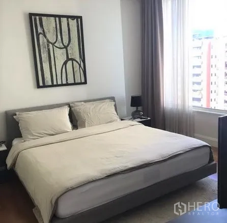 คอนโด ให้เช่าในPathum Wan, Bangkok - ห้องนอนหลักเตียงคิงไซซ์ มีภาพตกแต่งและหน้าต่างชมวิวเมืองพร้อมผ้าม่านยาว