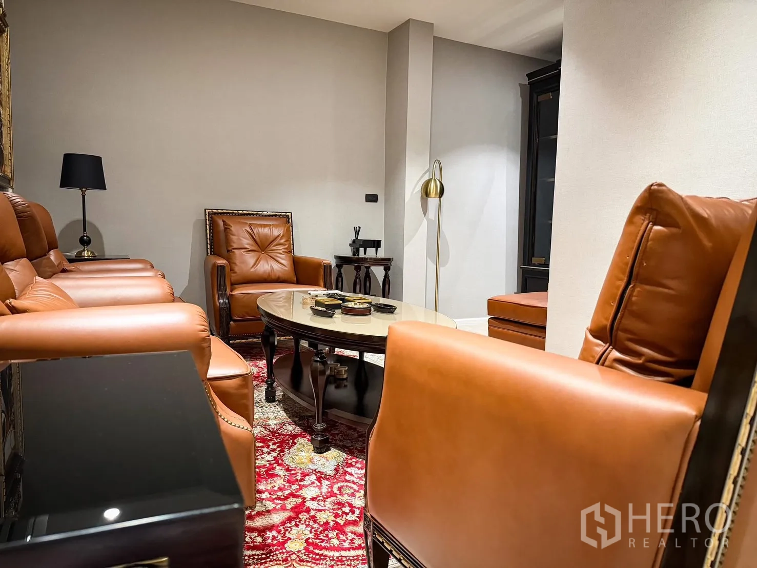 Detached House for rent or sale in Lak Si, Bangkok - Cozy lounge with caramel leather armchairs around a coffee table on a red patterned rug.