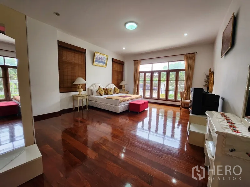 独立式住宅 出租在Prawet, Bangkok - 采光充足的卧室，大窗与阳台门，地面为亮面木地板。