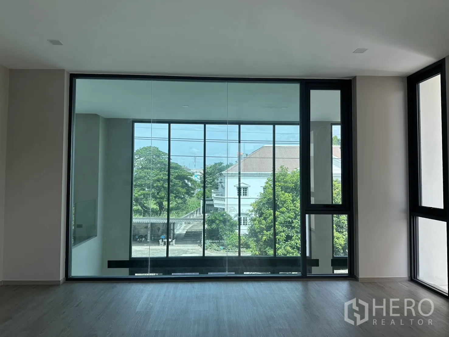 Home Office for rent or sale in Suan Luang, Bangkok - Interior glass wall looking toward a windowed room and greenery.
