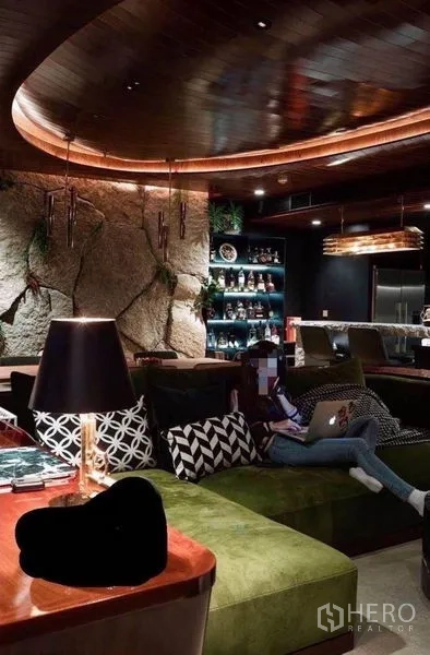 公寓 出租在Watthana, Bangkok - 休闲区大转角沙发、背光展示架，后方连接吧台与厨房