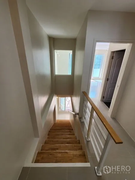 Townhouse for rent in Wang Thonglang, Bangkok - Stairwell with wooden steps and daylight from a window.