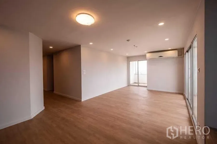 คอนโด ขายในChatuchak, Bangkok - ห้องนั่งเล่นกว้าง พื้นไม้ ฝ้าไฟดาวน์ไลท์ แอร์แขวนผนัง และประตูกระจกบานเลื่อนออกสู่ระเบียง