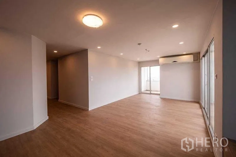 คอนโด ขายในChatuchak, Bangkok - ห้องนั่งเล่นกว้าง พื้นไม้ ฝ้าไฟดาวน์ไลท์ แอร์แขวนผนัง และประตูกระจกบานเลื่อนออกสู่ระเบียง