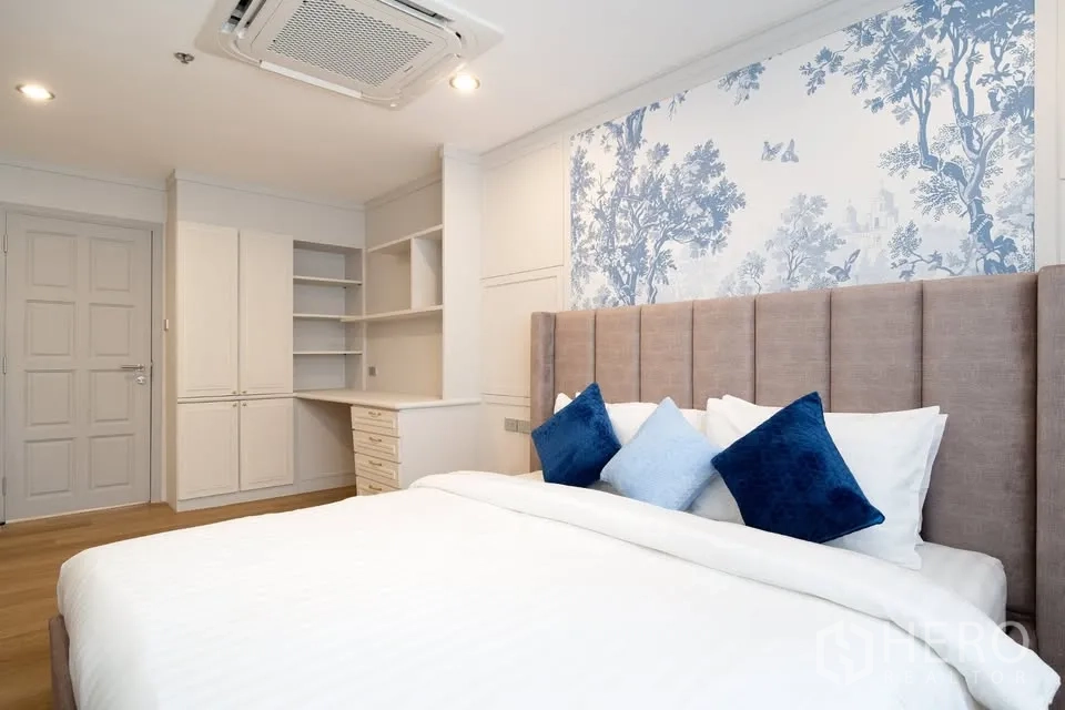 คอนโด ขายในBang Na, Bangkok - ห้องนอนหลักหัวเตียงบุผ้า ผนังลายฟีเจอร์สีน้ำเงิน พร้อมตู้และชั้นเก็บของบิวท์อิน