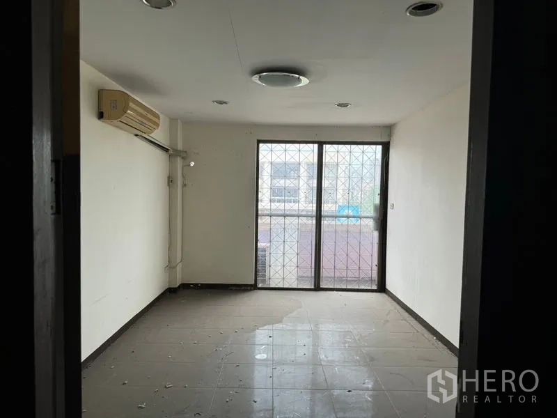 Shophouse for rent in Watthana, Bangkok - Unfurnished room with tiled floor, wall air conditioner and sliding door to a small balcony.