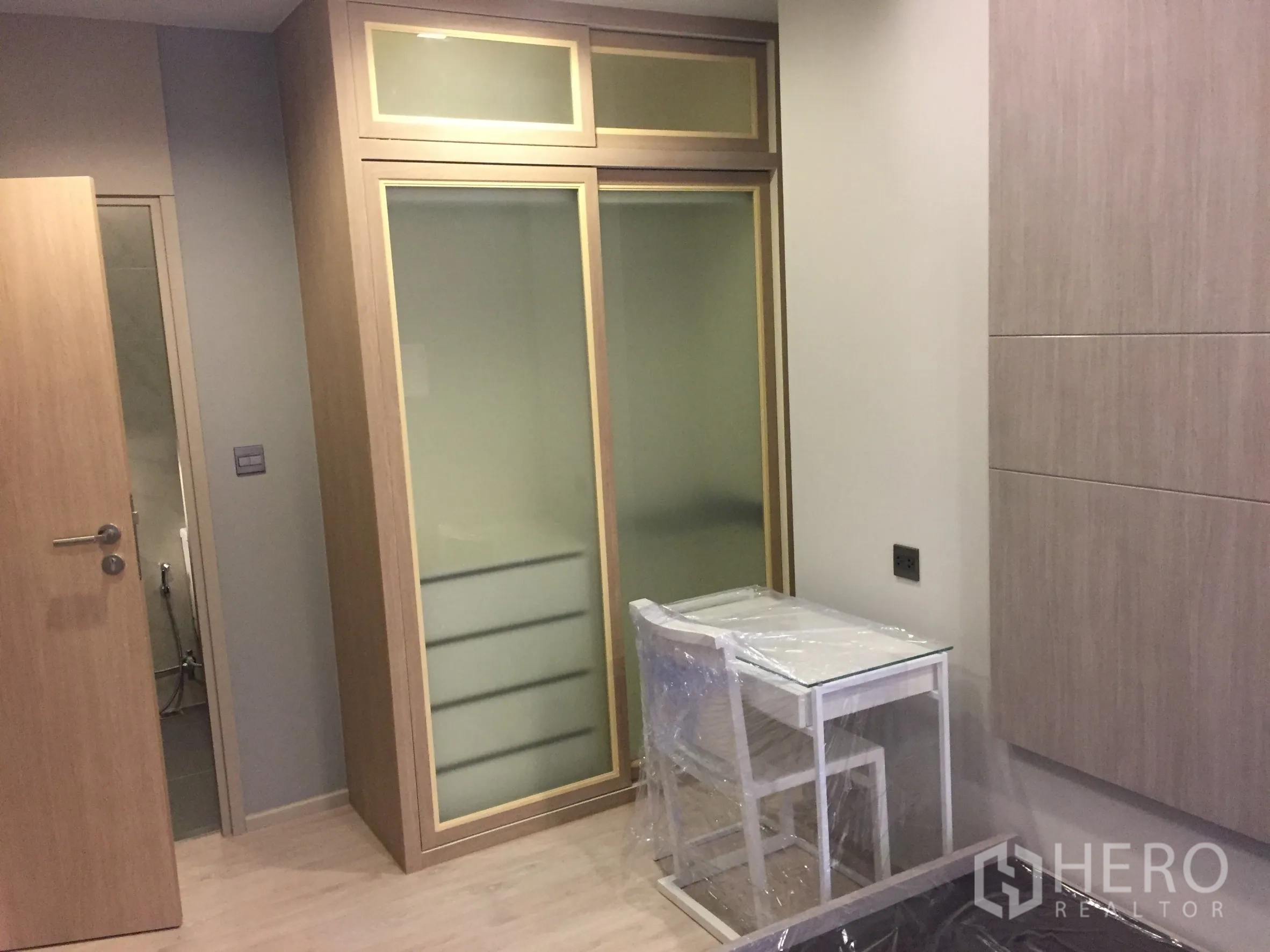 公寓 出租在Watthana, Bangkok - 卧室配内置推拉衣柜与小型书桌，浅木色饰面。