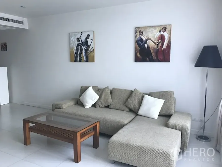 公寓 出租在Ratchathewi, Bangkok - 客厅一角，布艺转角沙发、玻璃茶几、落地灯与白色地砖。