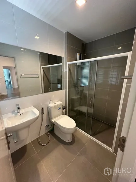 Detached House for rent or sale - Contemporary bathroom with glass-enclosed shower, large mirror, wall-hung sink and gray tiles.