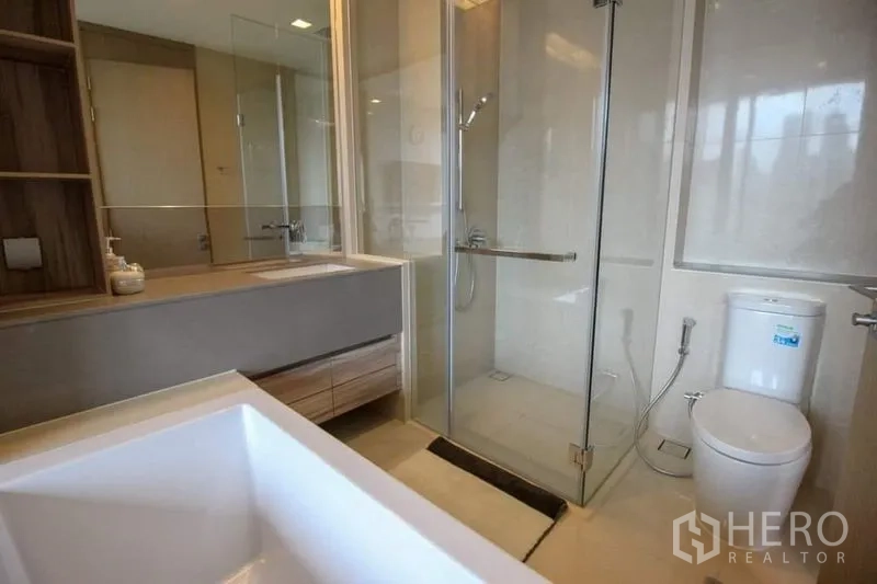 Condominium for sale in Watthana, Bangkok - Bright bathroom featuring a glass-enclosed shower, floating vanity and toilet.