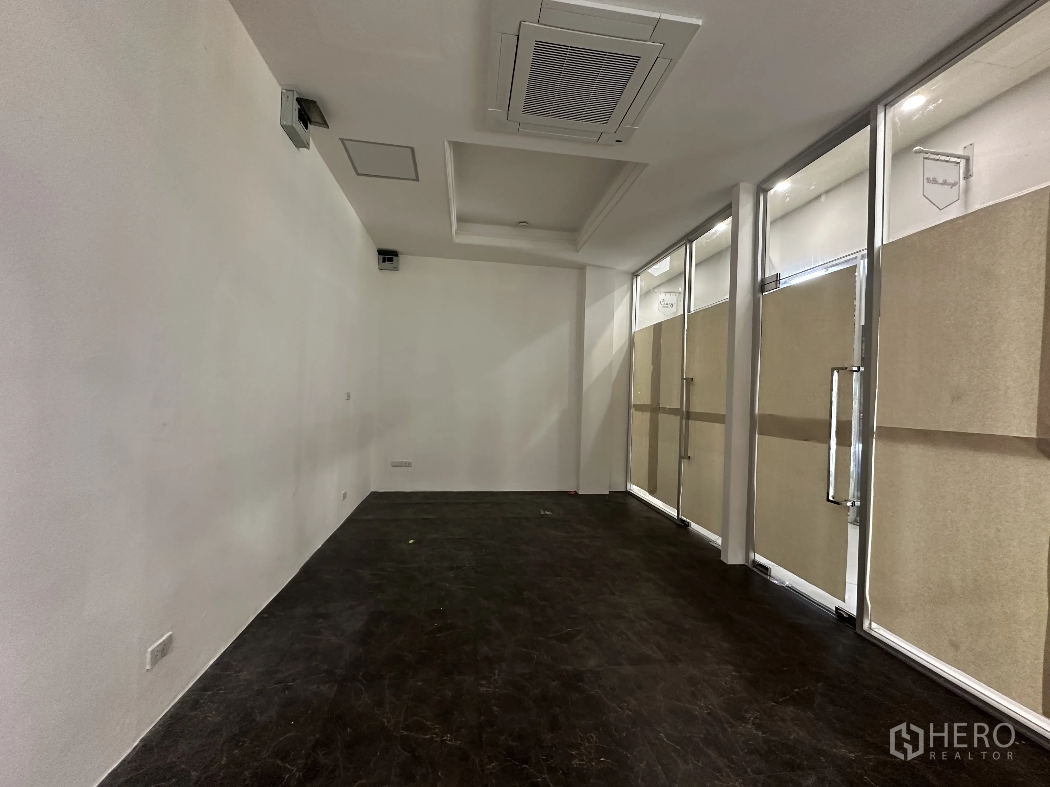 零售空间 for rent in Khlong Toei, Bangkok - 狭长型室内空间，配有筒灯照明、玻璃隔断和墙面电源插座。